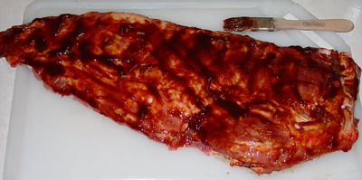 Uncooked Spareribs with BBQ sauce on them.