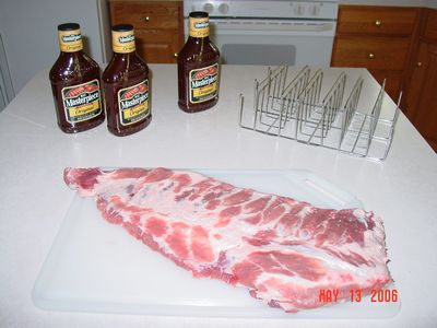Raw Spareribs with rib rack and bottled BBQ sauce